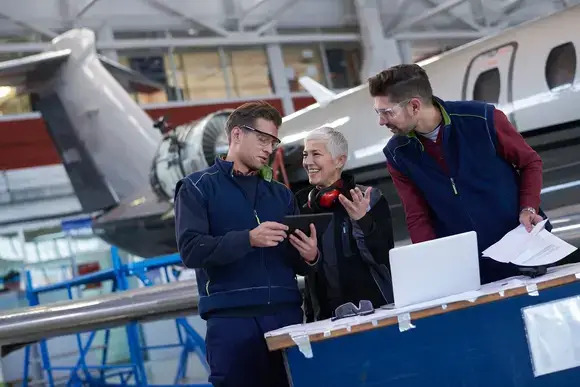 Three individuals pose together in front of a large airplane, showcasing a moment of excitement and adventure.