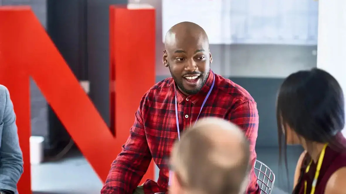 A diverse group of professionals engaged in discussion while seated around a conference table in an office setting.