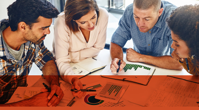 Four people collaborating on a project, analyzing graphs together in a professional setting