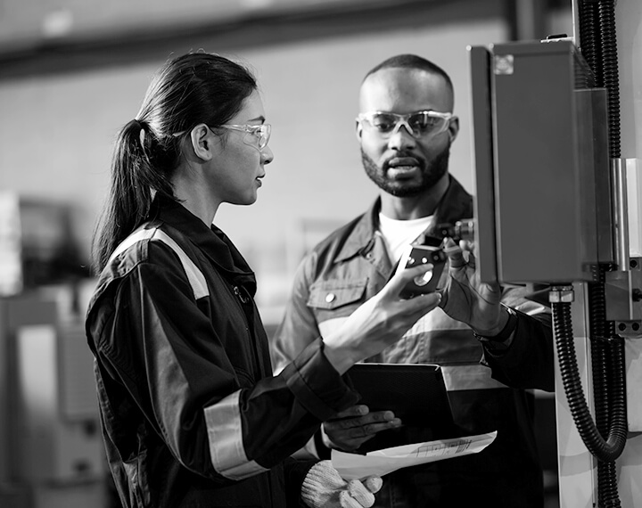 Two individuals in black and white stand side by side, engaged in technical checks.