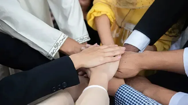 A diverse group of professionals in business attire standing together, holding hands in a display of unity and collaboration.