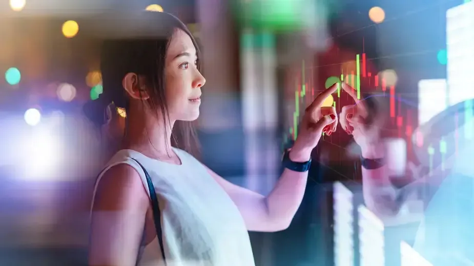 A woman gazes intently at a screen displaying a stock market graph, analyzing financial trends and data.