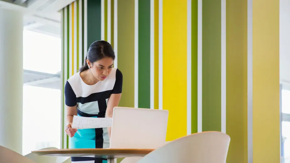 A woman smiles brightly while holding a cell phone in her hand, exuding joy and positivity.